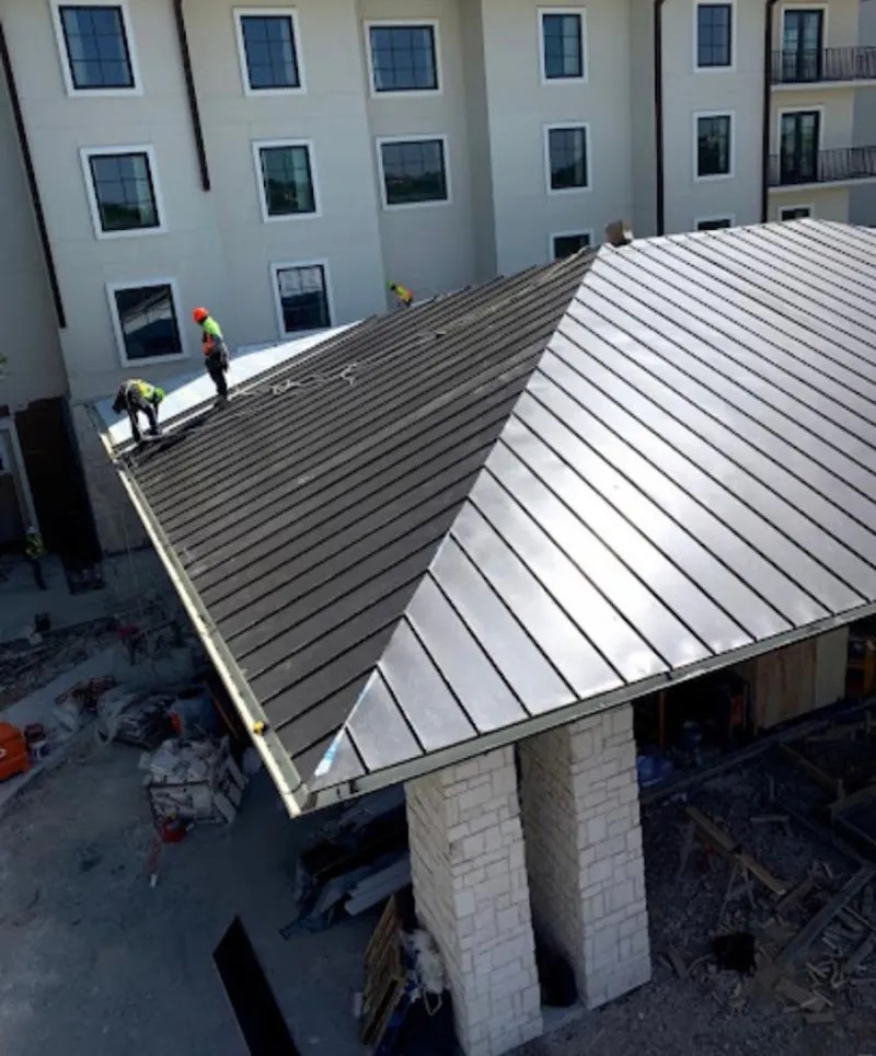 Crew installing standing seam metal roof panels on a commercial project in Plymouth